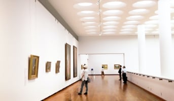 a picture showing a person looking at an art piece in a gallery.